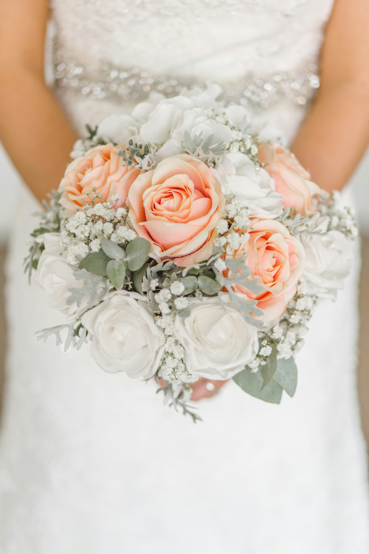 Bride holding a peach and white rose bouquet